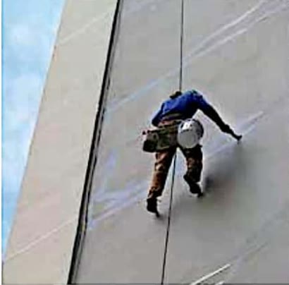 Alpinista industrial descendo por corda em fachada